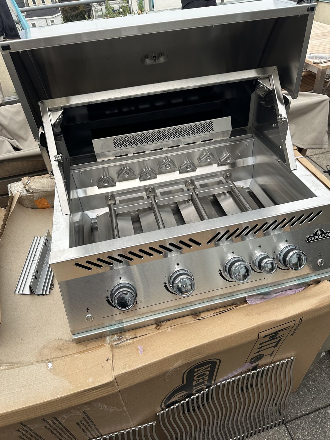 Built-in stainless steel grill installed with the lid open and burners visible