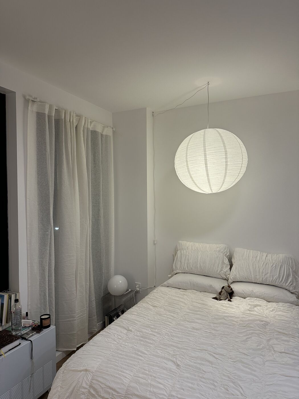 Glowing round paper pendant light installed above a bed